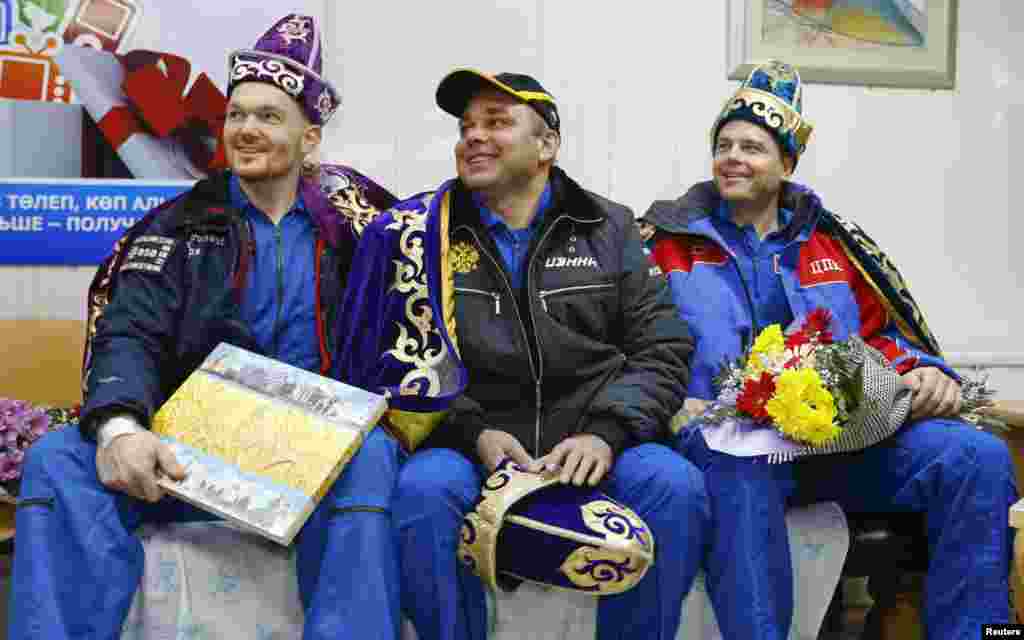 International Space Station crew members Alexander Gerst of Germany (left), Maxim Surayev of Russia (center), and Reid Wiseman of the United States are presented with the Kazakh national costume during a news conference. The three returned safely to Earth with a parachute landing of their Soyuz capsule in Kazakhstan, ending 5 1/2 months in orbit. (Reuters/Shamil Zhumatov)