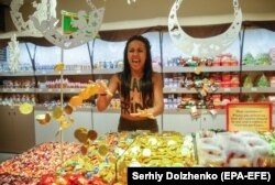 O activistă FEMEN cu sloganul 'Black Friday' strigând 'Sale Roshen' și atuncând bomboane în magazinul Roshen din Kiev.