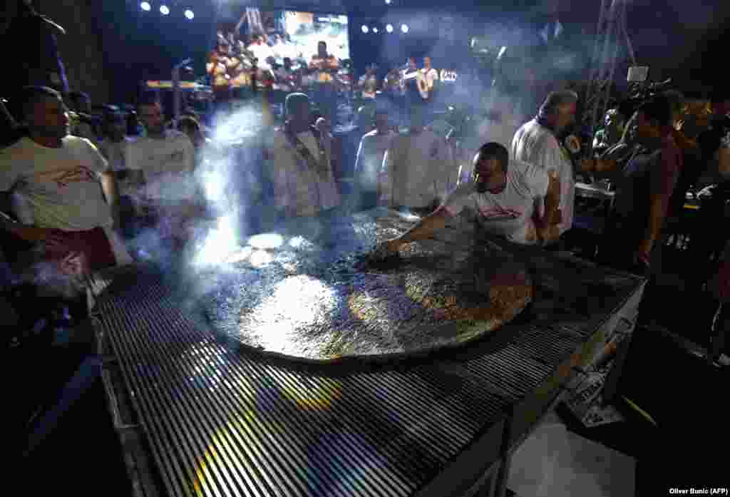 People watch chefs preparing a giant burger, known as pljeskavica, weighing 6.1 kilos at a grill festival in Leskovac, Serbia. (AFP/Oliver Bunic)