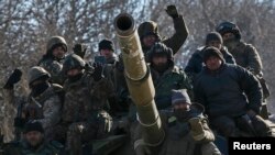 Ukrainian servicemen ride on a tank as they leave area around Debaltseve, February 18, 2015.