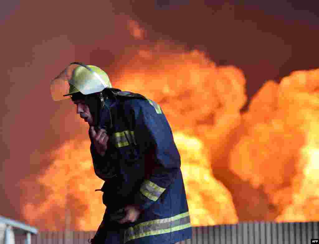 Пожежник кашляє, перебуваючи на території, де палають резервуари з нафтою