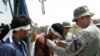 An ID card is placed around the neck of an Iraqi being released from a U.S. detention center prior to a reconciliation ceremony. In his hand is the Koran. There are slightly more than than 10,000 Iraqis in U.S. custody.