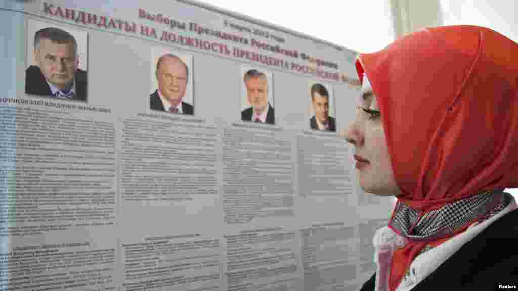 A woman looks at a list of presidential candidates at a polling station in Grozny, Chechnya