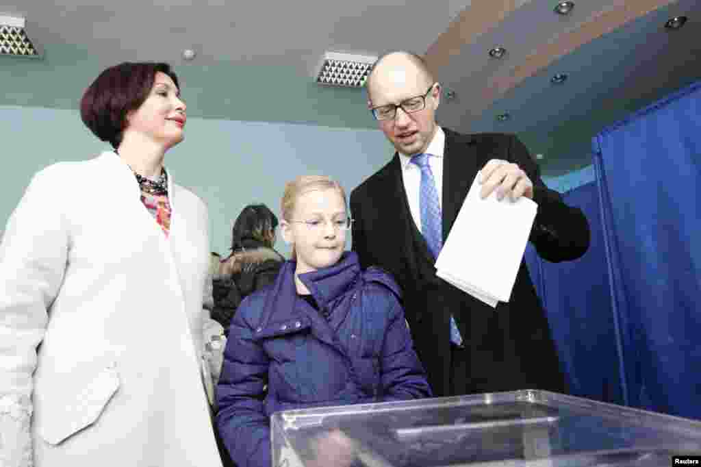 Ukraine's Prime Minister Arseniy Yatsenyuk (right) casts his ballot, as his daughter Sofiya (center) and wife Teresiya stand nearby, during parliamentary elections at a polling station in Kyiv on October 26. (Reuters/Gleb Garanich)