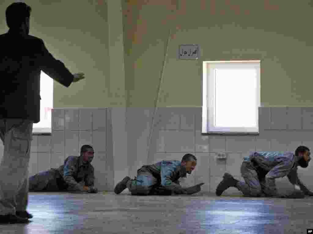 Afghan police officers duck for cover after a mortar hit the compound of the National Police Training Center during an inauguration ceremony in central Wardak Province on June 15.Photo by Gemunu Amarasinghe for AP