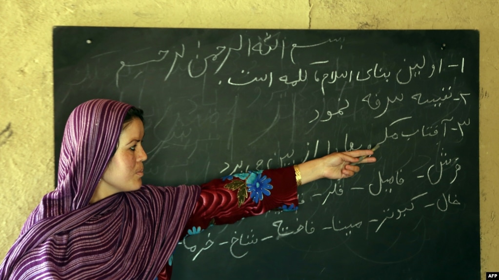 آرشیف: افغانستان ــ یک معلم سوادآموزی افغان، در جریان یک صنف، کلمات را برای دانش‌آموزان تلفظ می‌کند. بامیان سال ۲۰۱۴ میلادی