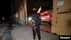 Naoružani militant Hamasa stoji na straži dok vozilo Crvenog krsta stiže da preuzme tela preminulih talaca koji su bili držani u Gazi od smrtonosnog napada 7. oktobra 2023. godine, 14. oktobra 2025.
