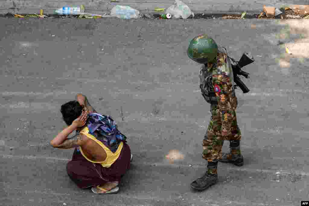 A soldier stands next to a detained man during a demonstration against the military coup in Mandalay on March 3, 2021.