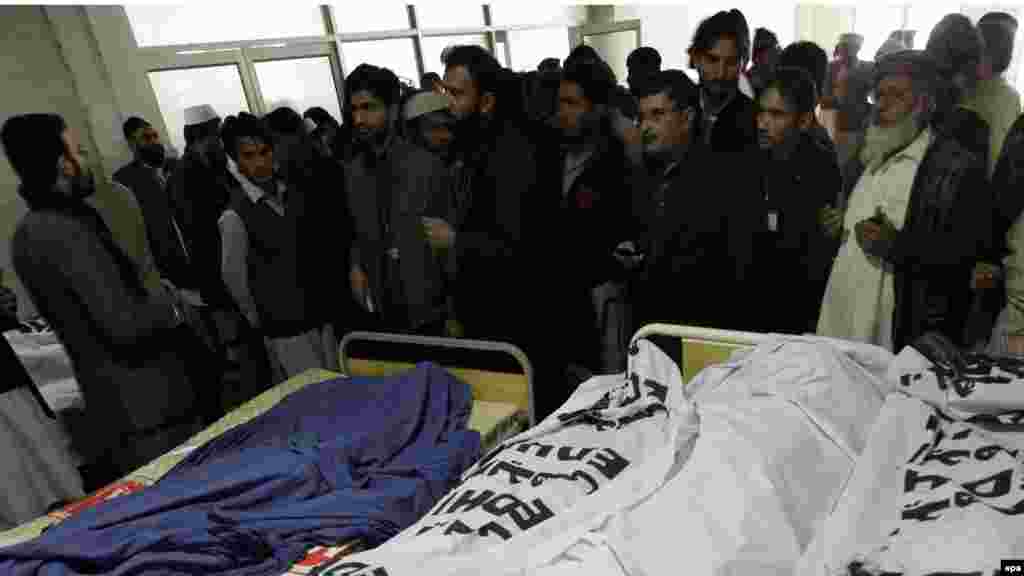 Relatives and rescue workers stand beside the bodies of schoolchildren who were killed in the Taliban attack.