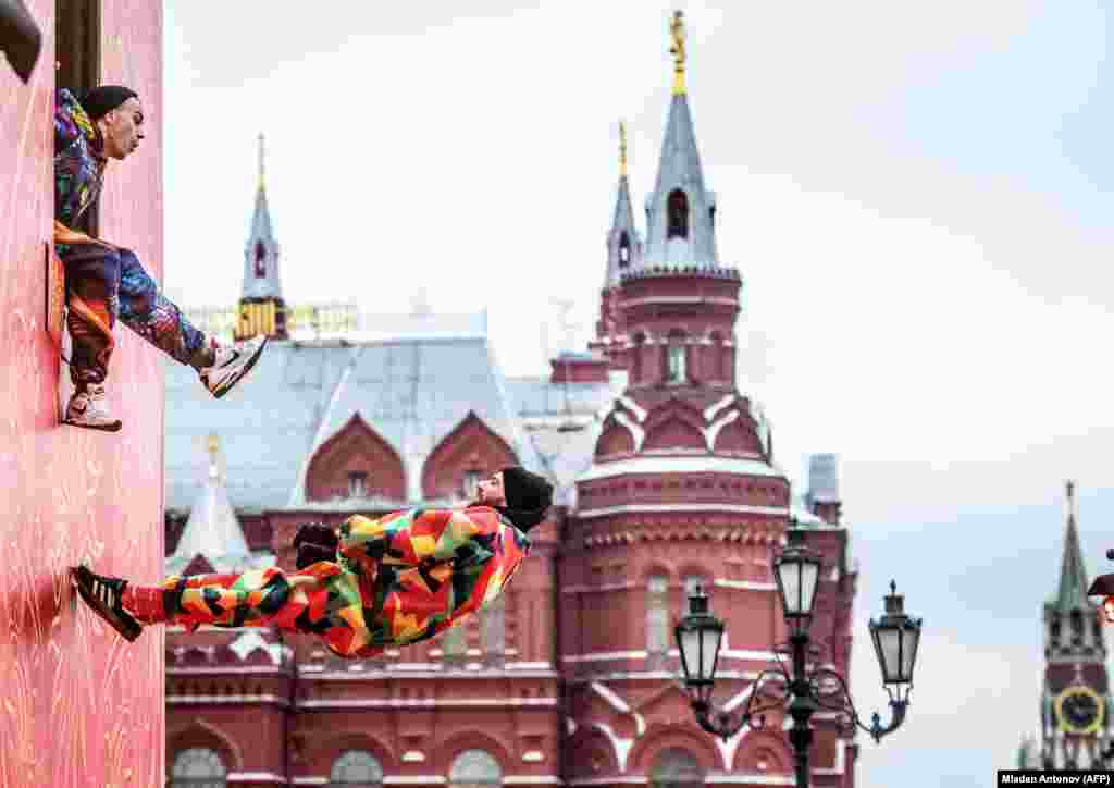 Акробаты выступают на Тверской улице недалеко от Кремля. Шествия ряженых - одна из традиций встречи Рождества в России.