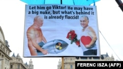 Плакат с изображением Владимира Путина и Виктора Орбана во время акции солидарности с Украиной в Будапеште, 2 апреля 2022 года. Надпись гласит: "Пошли ты его, Виктор! У него, может, и большая бомба, но всё, что за ней, уже вяленькое!" 