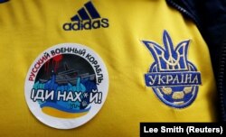 Український вболівальник демонструє наклейку на футболці перед відбірковим матчем Чемпіонату світу з футболу 2022 між Україною і Шотландією. Глазго, Велика Британія, 1 червня 2022 року
