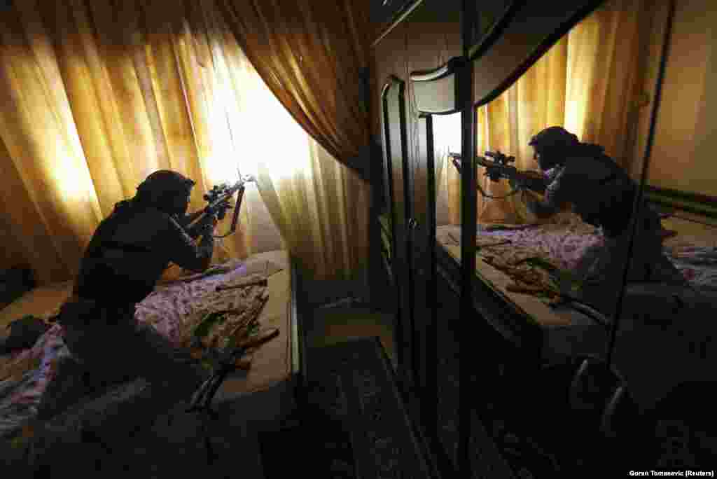 Баец са Свабоднай сырыйскай арміі страляе са снайпэрскай вінтоўкі з дома падчас баёў у ваколіцах Дамаска.&nbsp;