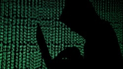 ILLUSTRATION -- FILE PHOTO: A hooded man holds a laptop computer as cyber code is projected on him in this illustration picture taken on May 13, 2017. 