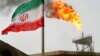 FILE PHOTO: A gas flare on an oil production platform is seen alongside an Iranian flag in the Gulf July 25, 2005.
