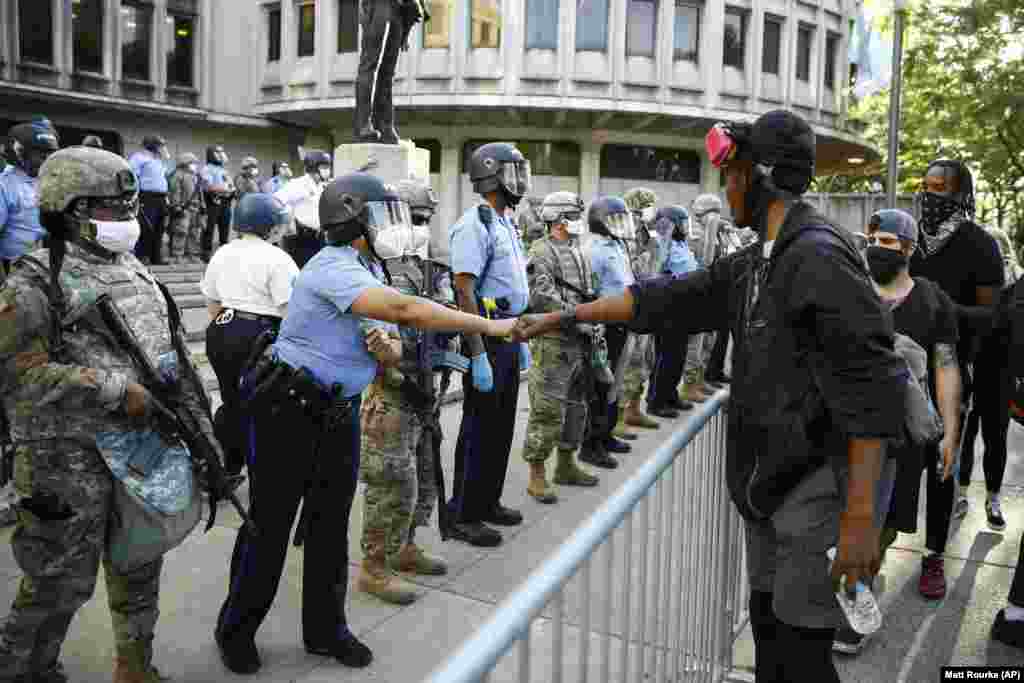 A protester fist-bumps Philadelphia police officer after police and Pennsylvania National Guard take a knee at the suggestion of Philadelphia Police Deputy Commissioner Melvin Singleton, unseen, outside Philadelphia Police headquarters in Philadelphia, Monday, June 1, 2020 during a march calling for justice over the death of George Floyd, Floyd died after being restrained by Minneapolis police officers on May 25. (AP Photo/Matt Rourke)&nbsp;