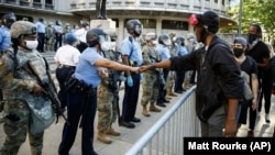 A protester fist-bumps Philadelphia police officer after police and Pennsylvania National Guard take a knee outside Philadelphia Police headquarters in Philadelphia, Monday, June 1, 2020.