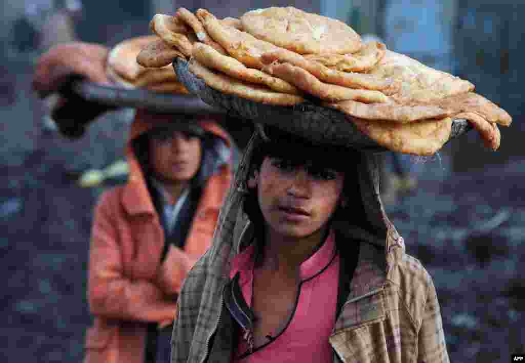 Afghan children look on as they wait for customers while selling food on a street in Kabul on December 8. (AFP/Aref Karimi)