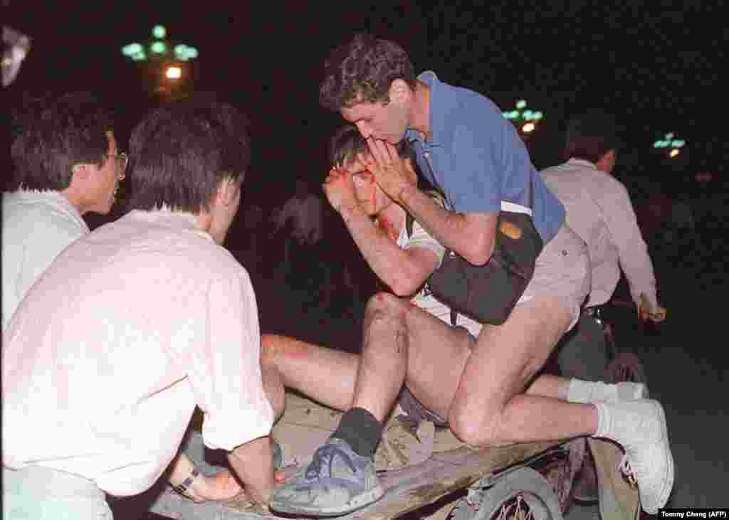 An unidentified foreign journalist (2nd-right) is carried out from the clash site between the army and students near Tiananmen Square on June 4, 1989.