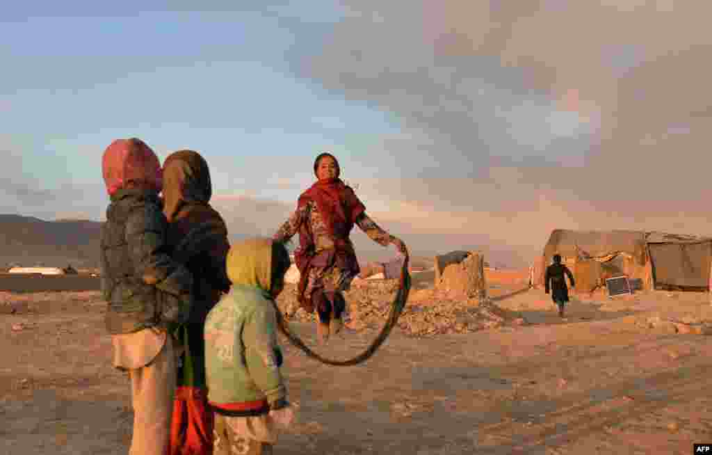 Internally displaced Afghan children watch a girl play with a jump rope at a refugee camp in Ghazni. (AFP/Sayed Zakeria)