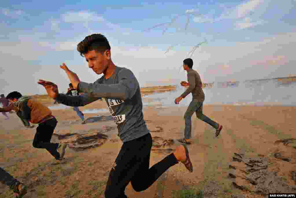 Palestinians run for cover from tear gas during clashes near the border between Israel and Khan Yunis in the southern Gaza Strip on November 9. (AFP/Said Khatib)