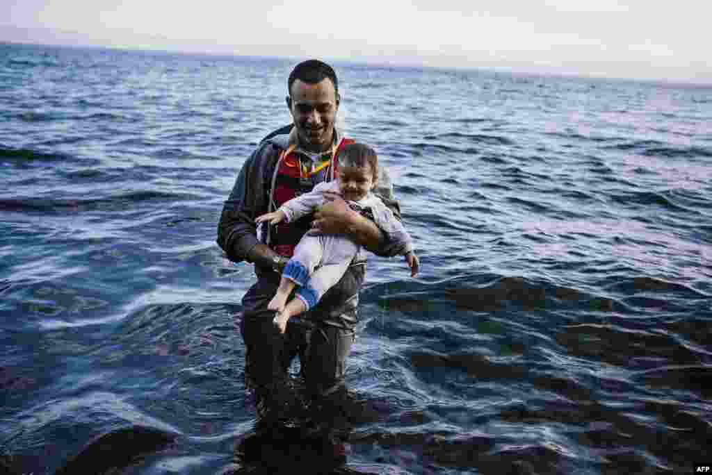 A man carries his child shortly after arriving with other refugees and migrants on the Greek island of Lesbos, after crossing the Aegean Sea from Turkey. (AFP/Dimitar Dilkoff)