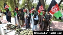 FILE: Former Taliban members hold national flags as they surrender their weapons during a reconciliation ceremony in in the eastern city of Jalalabad in August.