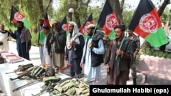 Former Taliban members hold national flags as they surrender their weapons during a reconciliation ceremony in the eastern Afghan city of Jalalabad on August 23.