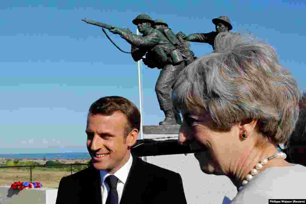 FRANCE -- French President Emmanuel Macron and British Prime Minister Theresa May greet officials after a Franco-British ceremony for the laying of the first stone of a British memorial in Ver-Sur-Mer as part of ceremonies to mark the 75th anniversary of&nbsp;the 75th anniversary of D-Day landings in Normandy, France, June 6, 2019.&nbsp; Macron and May spoke at a ceremony at Ver-Sur-Mer laying the cornerstone of a new memorial that will record the names of thousands of troops under British command who died on D-Day. Uniformed veterans in their 90s were present at the ceremony.
