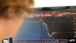 A woman looks at a chart showing the drop in the British pound against the U.S. dollar in London.