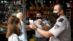 Georgia - Two security officers wearing face masks check temperature at the market entrance in central Tbilisi on June 3, 2020