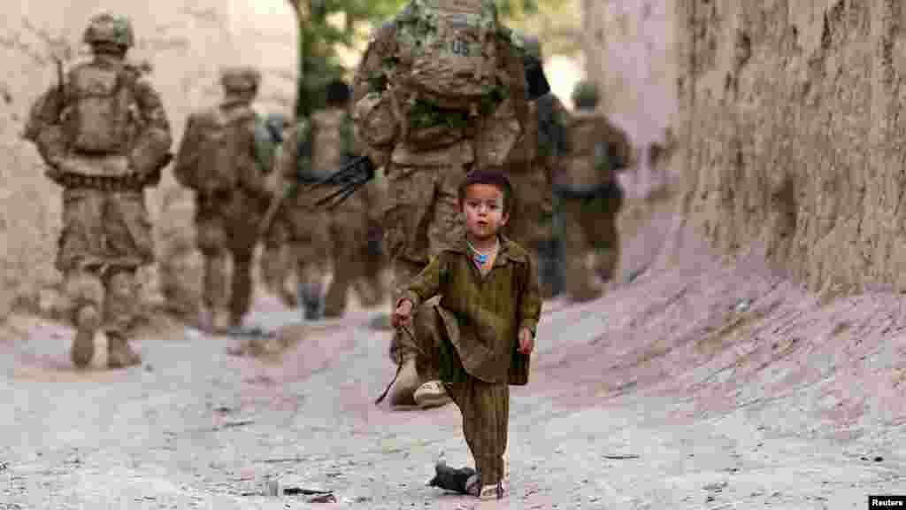 An Afghan boy plays on a street as U.S. Army soldiers patrol during a mission in the Zahri district of Kandahar Province on May 30. (Reuters/Shamil Zhumatov)