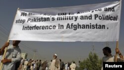 Men hold a banner aloft during a demonstration in Kabul against crossborder shelling attacks on August 30.