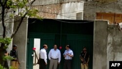 Pakistani security officials gather outside the former hideout of Al-Qaeda leader Osama bin Laden on May 4. The intelligence service called the failure to find bin Laden there "an embarrassment."