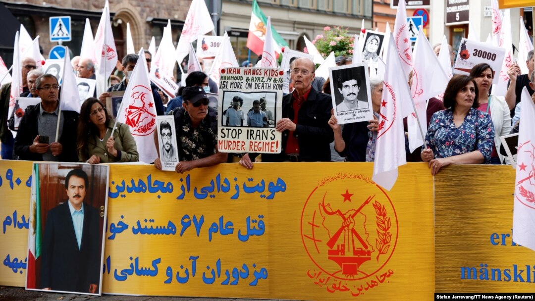 Susținătorii Organizației Populare Mujahedin din Iran protestează în fața Curții Districtuale din Stockholm în prima zi a procesului lui Hamid Noury, în vârstă de 60 de ani, acuzat de masacrarea prizonierilor politici din Iran în 1988. Fotografie realizată pe 10 august 2021.