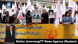Susținătorii Organizației Populare Mujahedin din Iran protestează în fața Curții Districtuale din Stockholm în prima zi a procesului lui Hamid Noury, în vârstă de 60 de ani, acuzat de masacrarea prizonierilor politici din Iran în 1988. Fotografie realizată pe 10 august 2021.