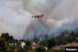 Un avion de stingere a incendiilor se îndreaptă spre combaterea acestora de lângă satul Rodopoli, la nord de Atena, Grecia, 27 iulie 2021.