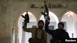 Rebel fighters hold weapons in front of the Hama governor's building after they captured the city during their advance across northern Syria on December 5.