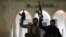 Rebel fighters hold weapons in front of the Hama governor's building after they captured the city during their advance across northern Syria on December 5.