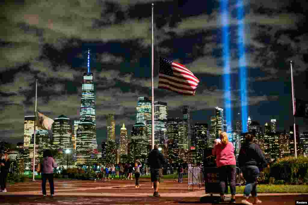 Oameni privesc instalația &bdquo;Tribute in Light&rdquo; din Liberty State Park, eveniment ce marchează cea de-a 19-a aniversare a atacurilor din 11 septembrie, New Jersey, SUA, 11 septembrie 2020. &nbsp;