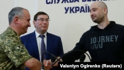 Russian journalist Arkady Babchenko (right) shakes hands with Ukrainian Security Service chief Vasyl Hrytsak (left) as Prosecutor-General Yuriy Lutsenko looks on at a news briefing in Kyiv on May 30.