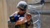 A U.S. Marine assigned to 24th Marine Expeditionary Unit comforts an infant while they wait for its mother during an evacuation at Hamid Karzai International Airport in Kabul at the weekend. 