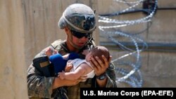 A U.S. Marine assigned to 24th Marine Expeditionary Unit comforts an infant while they wait for its mother during an evacuation at Hamid Karzai International Airport in Kabul at the weekend. 