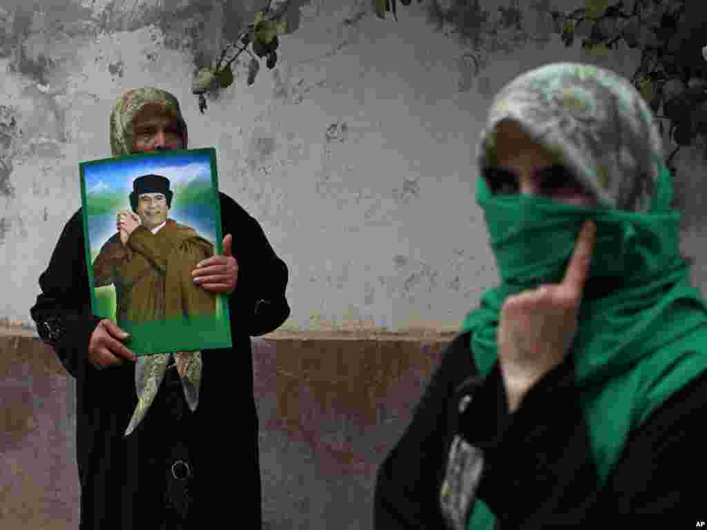 A woman holds up an image of Libyan leader Muammar Qaddafi during a protest in front of the Hungarian Embassy in Tripoli, Libya, on August 11. Dozens of reported residents of the town of Majar, where the Libyan government claims that 85 civilians were killed in a NATO air strike on August 9, protested in front of the embassy, which is currently representing the U.S. and the EU interests in Libya. Photo by Dario Lopez-Mills for AP