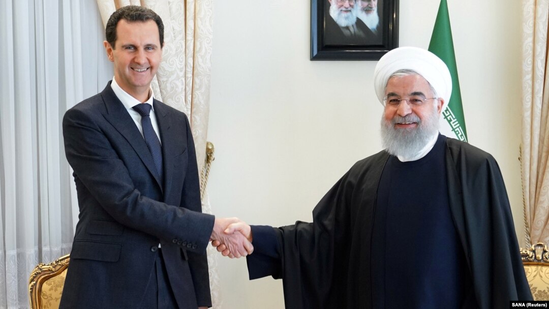 Syrian President Bashar al-Assad (left) shakes hands with Iranian President Hassan Rohani in Tehran in February 2019