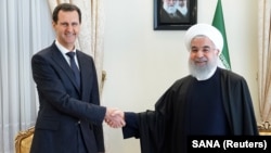 Syrian President Bashar al-Assad (left) shakes hands with Iranian President Hassan Rohani in Tehran in February 2019