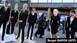 A woman walks past cutouts depicting presidential candidates Yuriy Boyko (left), Yulia Tymoshenko (2nd right), Volodymyr Zelenskiy (right), as well as Russian President Vladimir Putin (2nd left), oligarch Ihor Kolomoyskiy (3rd left) and politician Serhiy Taruta in Kyiv on March 28.