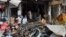 Pakistani merchants gather beside their damaged shops in Peshawar on September 30, the day after a bomb blast.