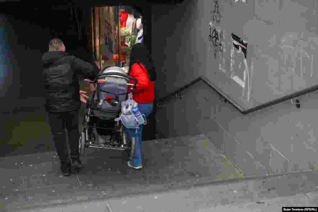 Një çift shihet duke e bartur pezull në dorë karrocën e fëmijës së tyre shkallëve të nënkalimit që ndodhet nën rrugën kryesore të lagjes "Dardania", një ndër lagjet në qendër të kryeqytetit.