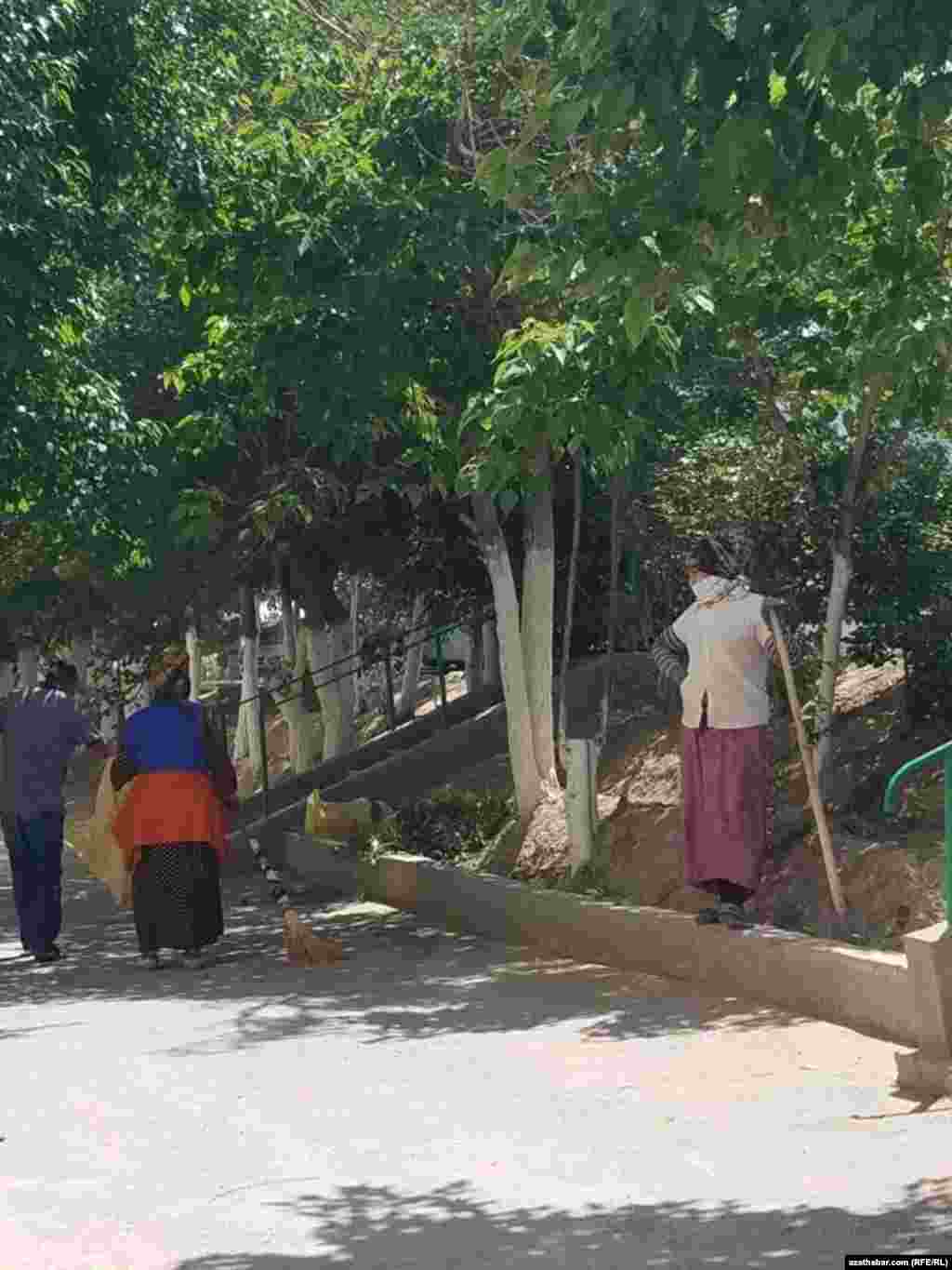 Şäheriň tämizlik, arassaçylyk işleri esasan aýal-gyzlaryň el güýji bilen amala aşyrylýar. Olar ýüz-gözlerini ýalyk bilen daňyp, ýelden-günden goranmaga çalyşýarlar. Aşgaýat, 2021.&nbsp;